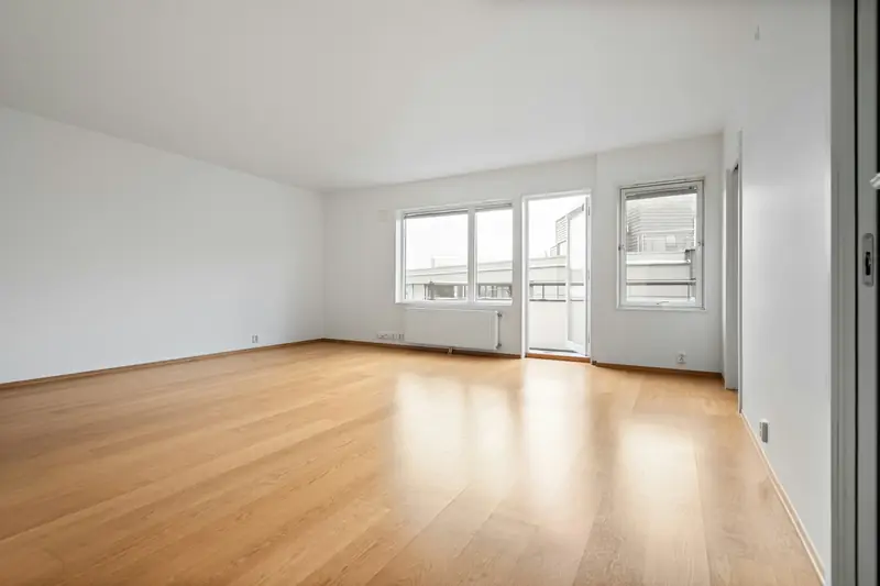 An empty room with wooden floors and white walls
