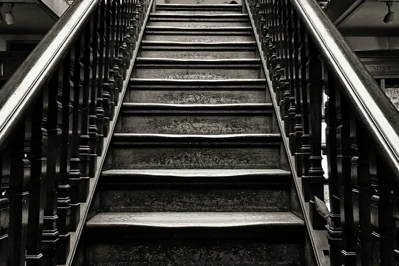 A narrow staircase with metal handrails rising between walls