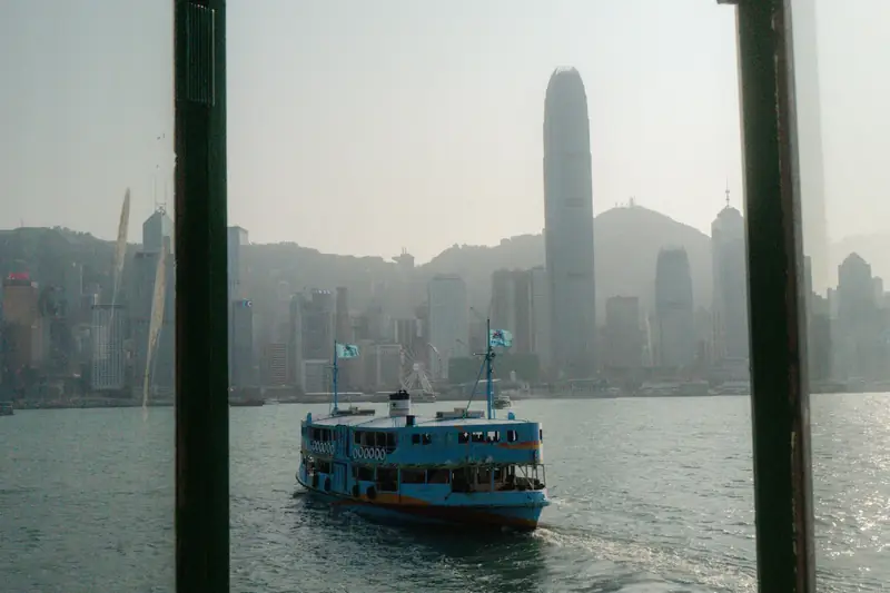 A ferry crossing Victoria Harbour under grey rain clouds, seen through a window